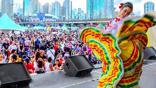 Une femme en costume coloré sur une scène avec le centre ville de Vancouver en arrière plan