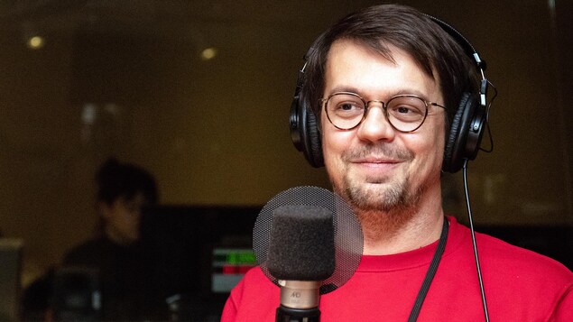 L'auteur et dramaturge Guillaume Corbeil sourit devant un micro.
