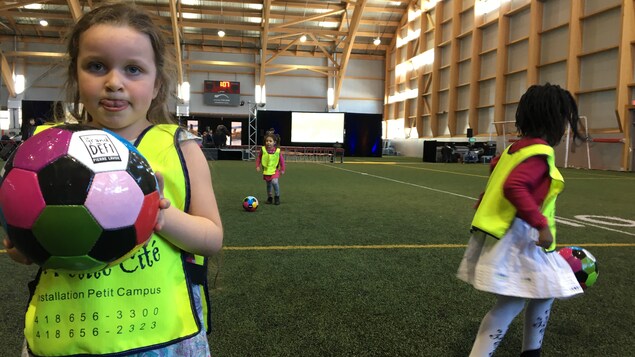 Une fillette tient un ballon de soccer dans ses mains au PEPS de l’Université Laval.