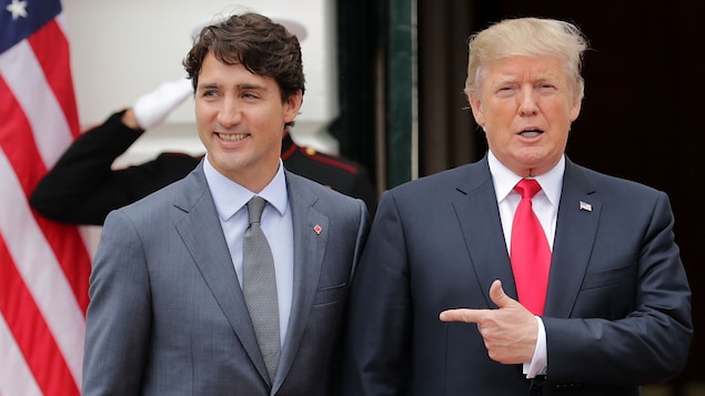 Le président Trump pointe Justin Trudeau du doigt alors que les deux hommes marchent  côte à côte. 