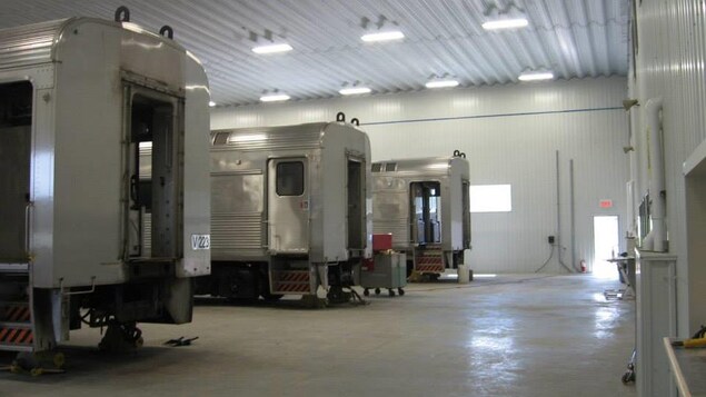 Trois wagons  de trains dans un entrepôt.