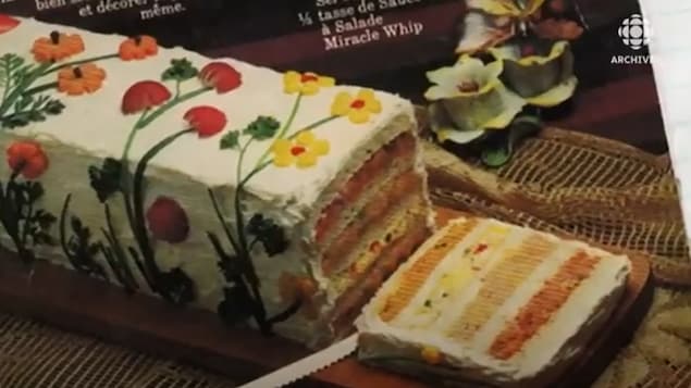 Un pain-sandwich à quatre étages avec un glaçage décoré de fleurs.