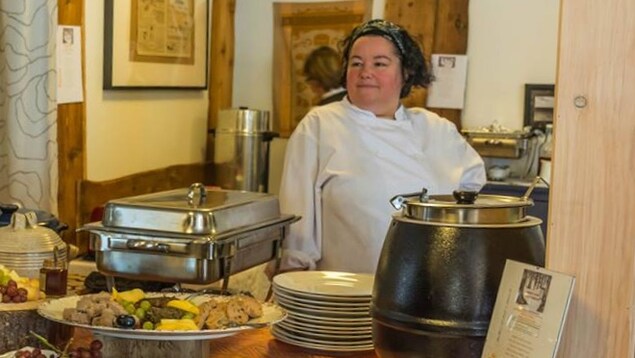 La chef Régine Morency devant de nombreux plats : des charcuteries, plats chauds, sushis