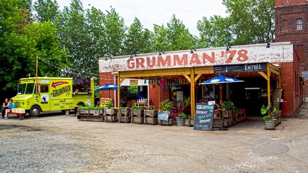 Un petit restaurant aménagé dans un garage, à côté duquel se trouve un camion de cuisine de rue.
