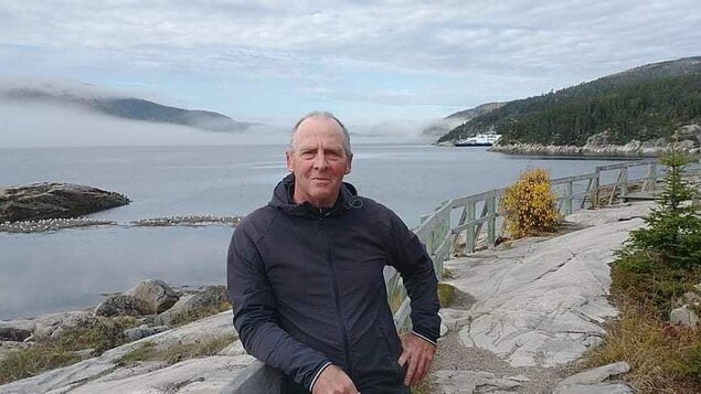 Richard Therrien est à l'extérieur près de l'eau et des rochers, dans le parc marin de Saguenay. Il sourit. 
