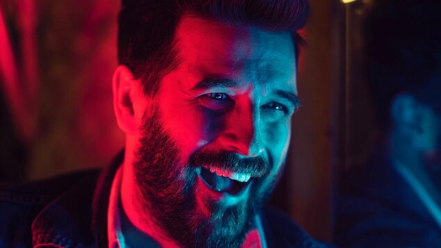 Ryan Doucette, sous des lumières bleues et rouges, tout souriant.