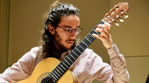 Un jeune homme qui joue de la guitare classique.