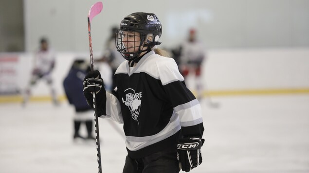Une jeune femme qui joue au hockey.