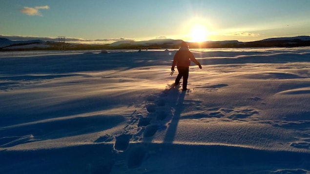 Une jeune femme traverse une étendue de neige en Basse-Côte-Nord. 