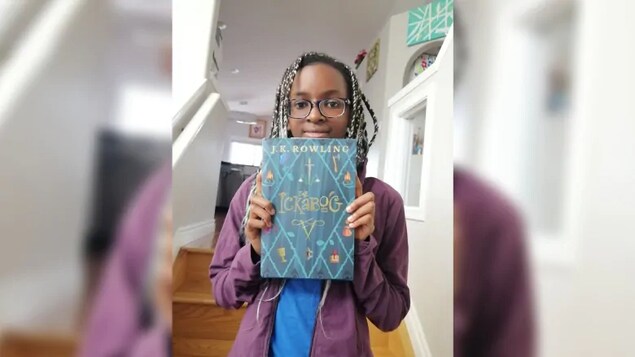 La jeune fille tient un livre dans une maison.