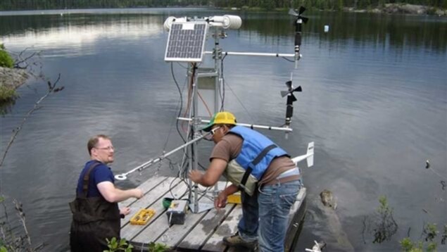 Deux scientifiques préparent une station météorologique qui flottera sur un lac dans la zone des lacs expérimentaux. Deux scientifiques préparent une station météorologique qui flottera sur un lac dans la zone des lacs expérimentaux.