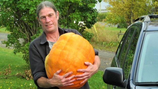 Louis Vallée tient une citrouille dans ses bras.