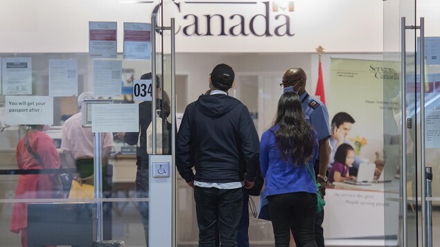 Des personnes attendent en file devant un bureau de Service Canada.