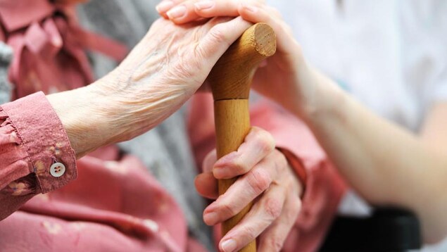 La main d'une infirmière repose sur celle d'une aînée. 