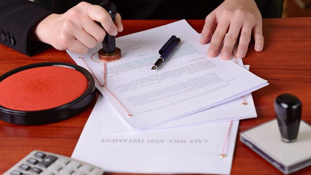 Une femme apposant une étampe sur un testament.