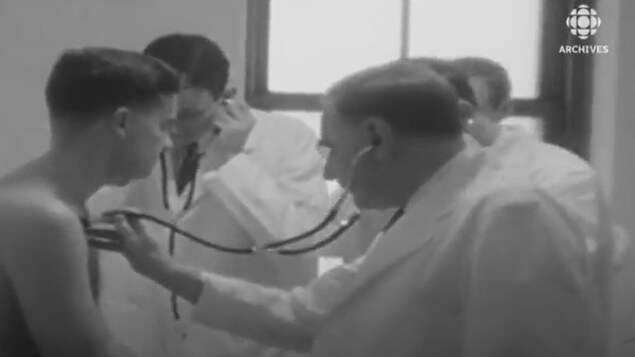 Un jeune homme est examiné par une équipe de médecins en 1957.