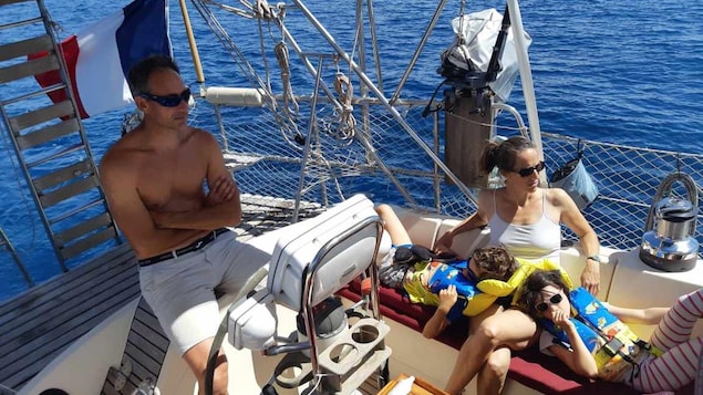 Laurent Torrecilles à la barre du voilier alors que Lynne et les enfants relaxent au soleil.