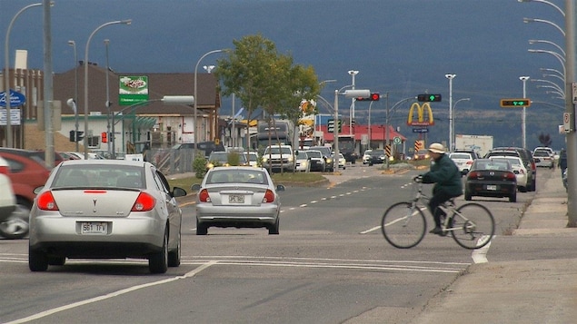 Le boulevard Laure, à Sept-Îles : des voitures, un cycliste et des feux de circulation.