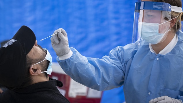 Une professionnelle de la santé effectue un test de dépistage du coronavirus dans une clinique mobile du quartier Saint-Michel.