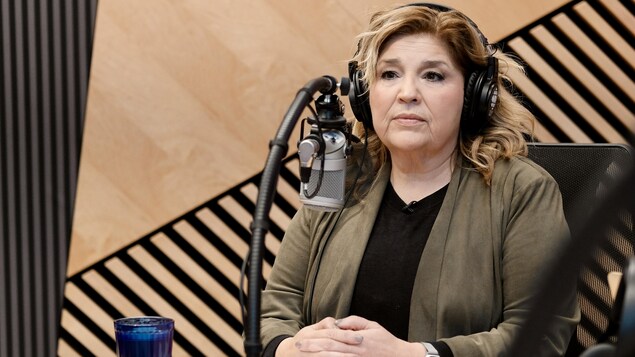 L'animatrice est assise en studio lors d'une entrevue.
