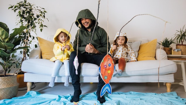 Papa qui pêche dans le salon avec ses filles. 