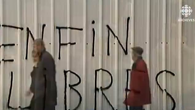 Des gens passent devant un graffiti à Tunis qui dit : Enfin libres.