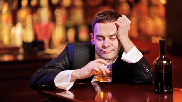 Un homme console sa peine en buvant de l'alcool.