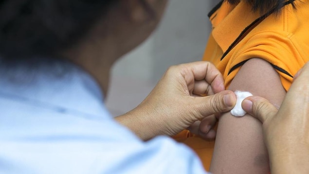 Una persona posiziona un batuffolo di cotone dove è stato iniettato il vaccino.
