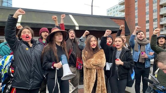 Des jeunes avec de la peinture rouge sur le visage sont en train de manifester dans la rue.