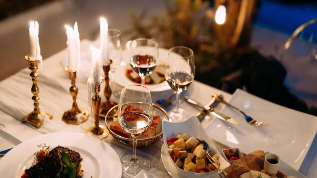 Une table sur laquelle se trouvent des chandelles, des verres de vin et un repas d'allure gastronomique.