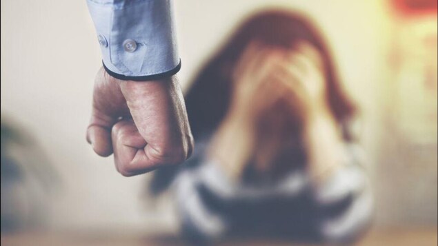 Un homme serrant le poing devant une femme qui porte les mains à son visage.