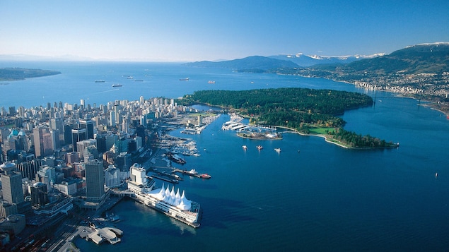 Vue aérienne du Parc Stanley et du centre-ville ouest de Vancouver. On voit des bateaux et les montagnes à l'horizon.