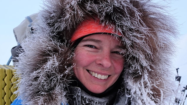 Une femme porte un manteau d'hiver dont le bord du capuchon est complètement givré.