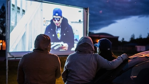 Un écran de cinéma en plein-air et des gens qui le regardent. Un écran de cinéma en plein-air et des gens qui le regardent.
