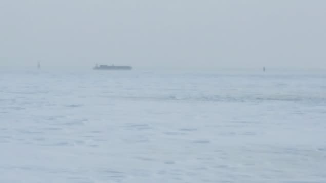 On aperçoit le bateau au loin, comme une tache entre le ciel nuageux et le fleuve glacé. On aperçoit le bateau au loin, comme une tache entre le ciel nuageux et le fleuve glacé.