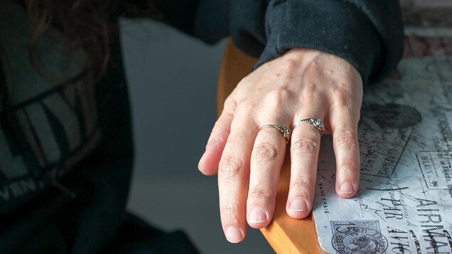Une main posée sur une table avec deux anneaux. 
