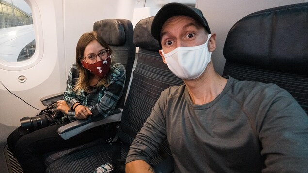 MJ Lalande et Alex Normand dans un avion. Tous deux portent des masques.