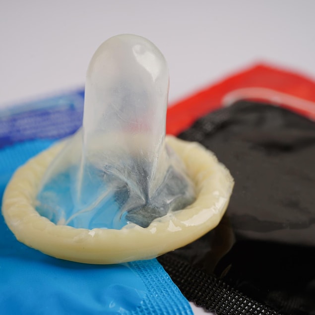 Un condom déballé est posé sur d'autres qui, eux, sont encore dans leur emballage.