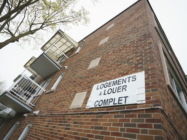 Une affiche accrochée à un immeuble porte la mention « logements à louer, complet ».