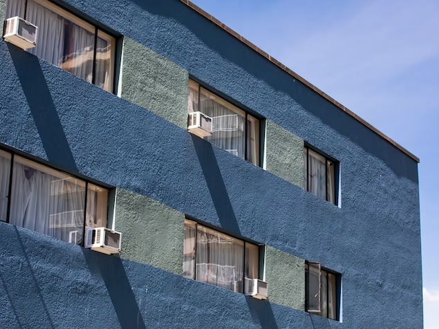 Un immeuble avec des climatiseurs installés à certaines fenêtres.