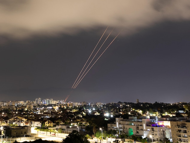 Vue de loin d'un système anti-missile en action durant la nuit dans une ville.
