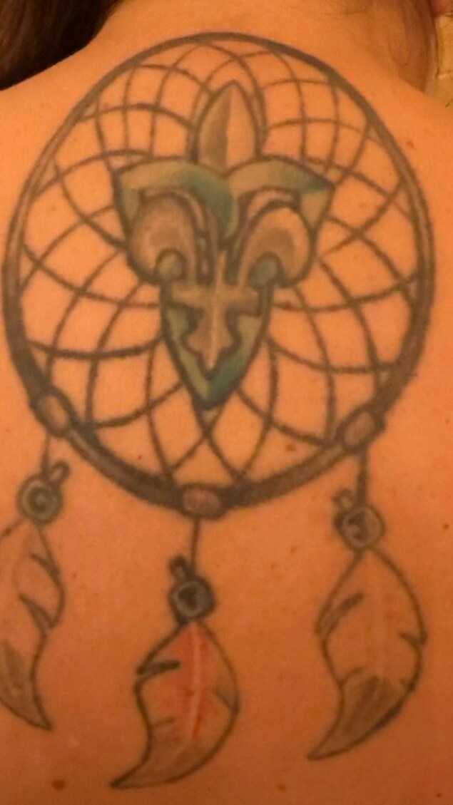 Tatouage d'une fleur de lys et d'un trille dans un capteur de rêves.