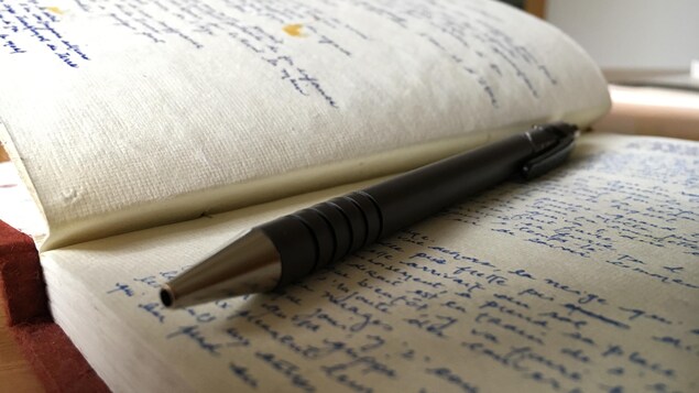 Un cahier ouvert sur un texte et un stylo posé dessus.