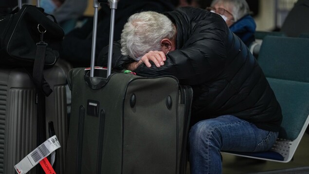 رجل وضع رأسه على حقيبة سفره في مطار فانكوفر الدولي.