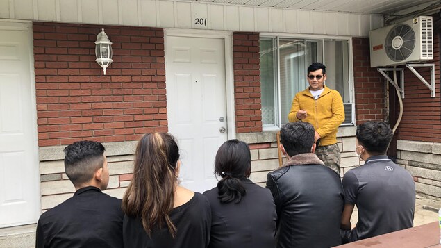 Un homme parle à cinq membres de sa famille, qui font dos à la caméra.