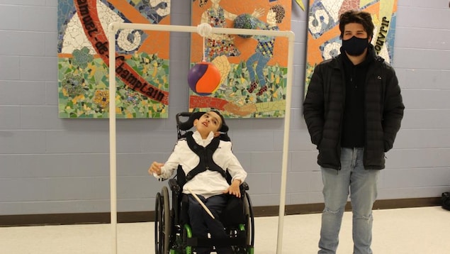 Ahmad Shiekh et Xabriel Imbeault devant un appareil composé de tuyau de plastique sur lequel est attaché un ballon.