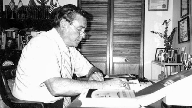 Une photo en noir et blanc d'Albert Dubé travaillant à son bureau.