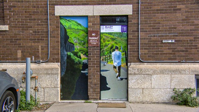 Une porte derrière une édifice du centre-ville de Saskatoon est peinturée en véritable oeuvre d'art.