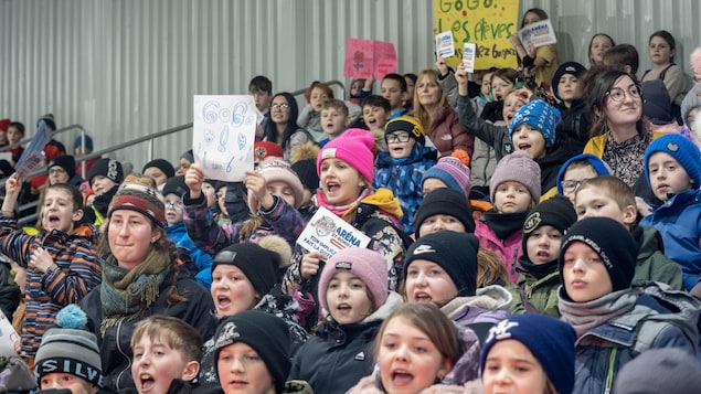 Des enfants assis dans un aréna.