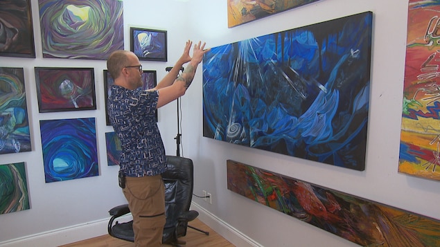 Steve St-Pierre présente les œuvres accrochées dans sa maison.